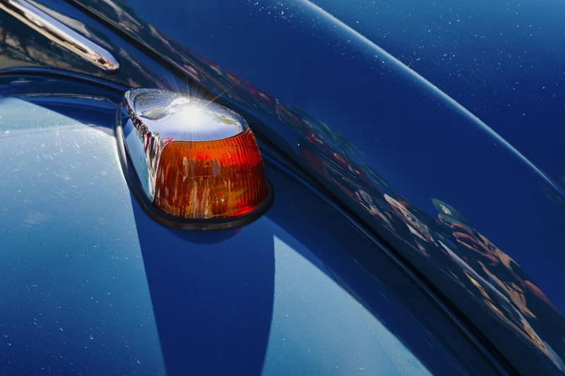 Verchromter Blinker mit orangem Glas auf blauem Lack eines Klassikers